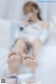 A woman sitting on a bed with her feet up in the air.