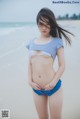 A young woman standing on a beach next to the ocean.