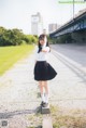 A woman in a white shirt and black skirt standing on a sidewalk.