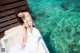 A woman in a white dress sitting on a bed in the water.