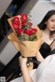 A woman holding a bouquet of red roses in her hands.