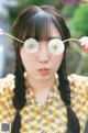 A woman holding a pair of dandelion seeds in front of her eyes.