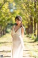 A woman in a white dress standing in a park.