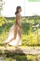 A woman in a long dress walking down a dirt road.