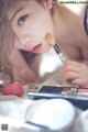 A woman laying on a bed with a makeup brush in her hand.