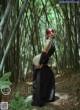 A woman in a black dress standing in a bamboo forest.