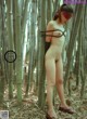 A naked woman standing in a bamboo forest.