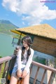 A woman sitting on a balcony next to a body of water.