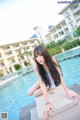 A woman sitting on the edge of a swimming pool.