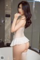 A woman in a white lingerie standing in a bathroom.