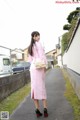 A woman in a pink dress is walking down the street.