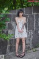 A woman standing in front of a stone wall.