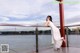 A woman in a white dress leaning against a railing.