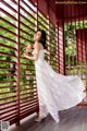 A woman in a white dress standing on a porch.