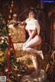 A woman in a red and white lingerie posing next to a Christmas tree.