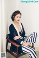 A woman sitting in a chair wearing striped pants.