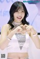 A woman in a white top making a heart with her hands.