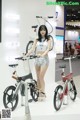 A woman standing next to two bicycles on display.