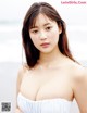 A woman in a white dress posing on the beach.