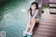 A woman in a blue bikini sitting on a wooden dock.