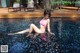 A woman in a pink bikini sitting in a pool.