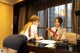 A woman in a skirt and a man in a suit sitting at a desk.