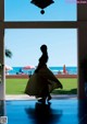 A woman in a long dress standing in front of a window.