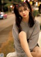 A young woman sitting on the side of a road.