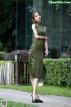 A woman in a green dress is walking down the street.