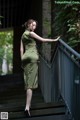 A woman in a green dress standing on a set of stairs.