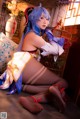 A woman with blue hair sitting on the floor next to a cage.