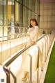 A woman in a white coat is standing on a railing.