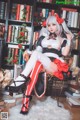 A woman sitting on a chair in front of a bookshelf.