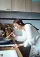 A woman in a white robe preparing food in a kitchen.