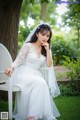 A woman in a wedding dress sitting on a white chair.