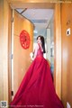 A woman in a red dress standing in an elevator.