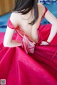 A woman in a red dress sitting on a bed.