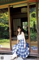 A woman sitting on a bench in front of a sliding glass door.