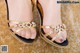 A close up of a woman's feet wearing a pair of gold sandals.