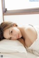 A woman laying on top of a bed next to a window.