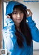 A woman in a blue hoodie leaning against a wall.