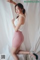 A woman in a white top and pink skirt posing for a picture.