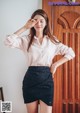 A woman in a pink shirt and black skirt posing for a picture.