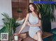 a woman sitting on top of a wooden table next to a plant