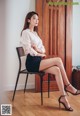 A woman sitting on a chair with her legs crossed.