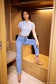 A woman sitting on top of a wooden shelf in a room.