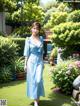 A woman in a blue dress walking through a garden.