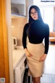 A woman wearing glasses standing in front of a washing machine.