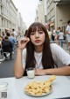 A woman sitting at a table with a plate of french fries and a glass of milk.