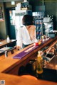 A woman standing behind a bar in a restaurant.